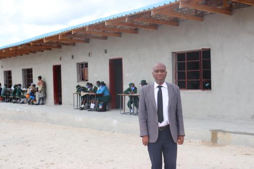 Masimba Nyabereka, Headmaster of Nyamubarawande Secondary School, standing in front of the two-classroom block the construction of which was led by ActionAid Zimbabwe and DOMCCP in 2020.